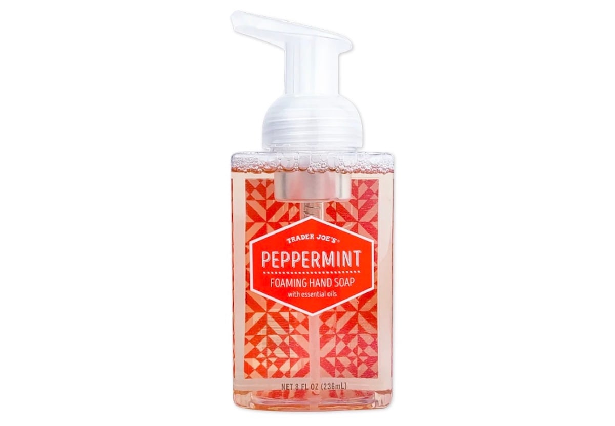 A clear pump bottle of Trader Joe's Peppermint Foaming Hand Soap with red geometric label and white text, filled with light pink liquid.