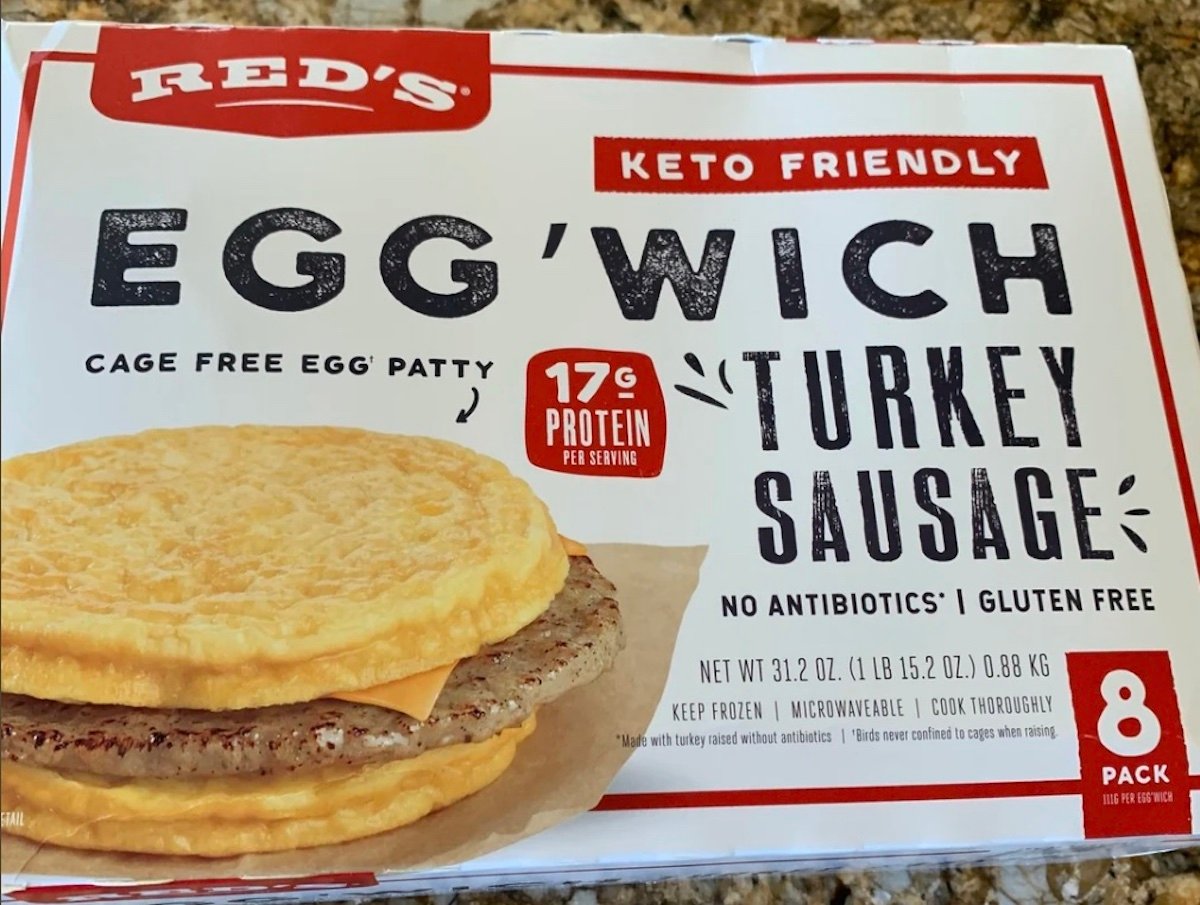 A box of Red’s Keto Friendly Egg’Wich Turkey Sausage sandwiches, featuring cage-free egg patties and 17g protein per serving. The packaging highlights gluten free, no antibiotics, 8-pack, and microwaveable.