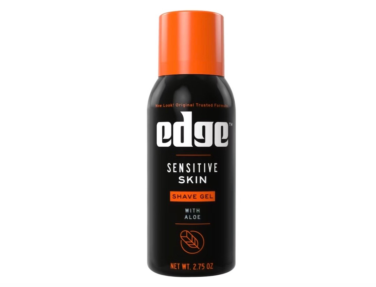 A can of Edge Sensitive Skin Shave Gel with Aloe, featuring an orange cap and a black label with white and orange text. The net weight is 2.75 ounces.