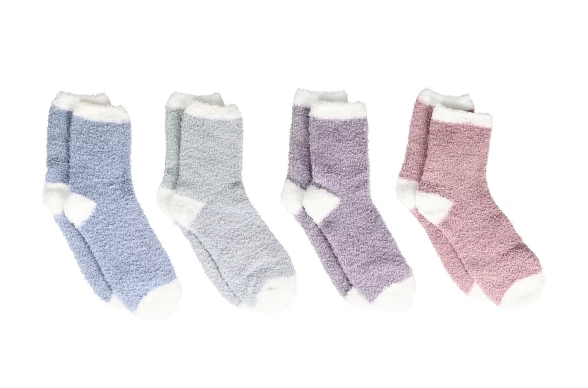 Four pairs of fuzzy socks in pastel colors—blue, light blue, lavender, and pink—each with white toes, heels, and cuffs, are arranged in a row on a white background.