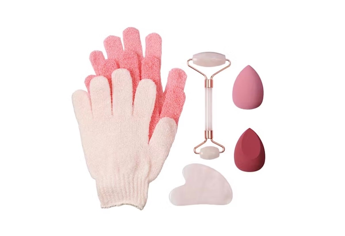 A pair of pink and white exfoliating gloves, a jade facial roller, a gua sha stone, and three pink makeup sponges, all arranged on a white background.