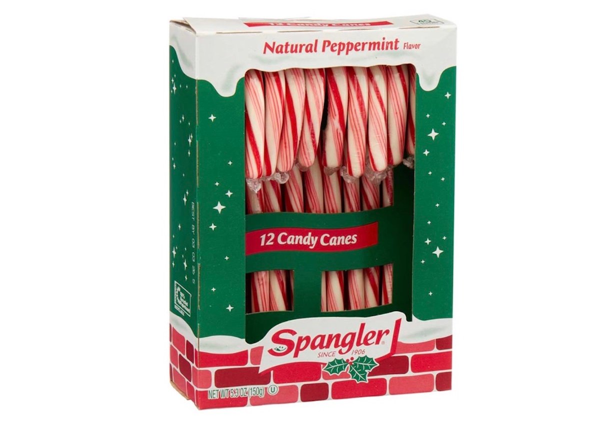 A green box decorated with brick and holly designs contains 12 red and white striped Spangler candy canes labeled "Natural Peppermint Flavor." The candy canes are visible through a clear window on the front.
