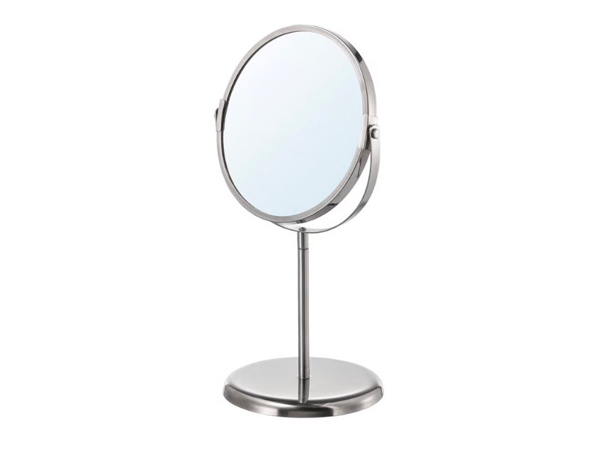 A round, freestanding tabletop mirror with a metal frame and stand, featuring an adjustable, tilting design.