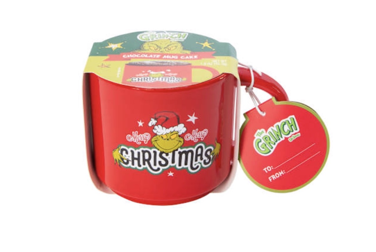 A red mug featuring a festive Grinch design and the words "Merry Grinchmas," packaged with a chocolate mug cake mix and a green and red gift tag that says "To: From:".