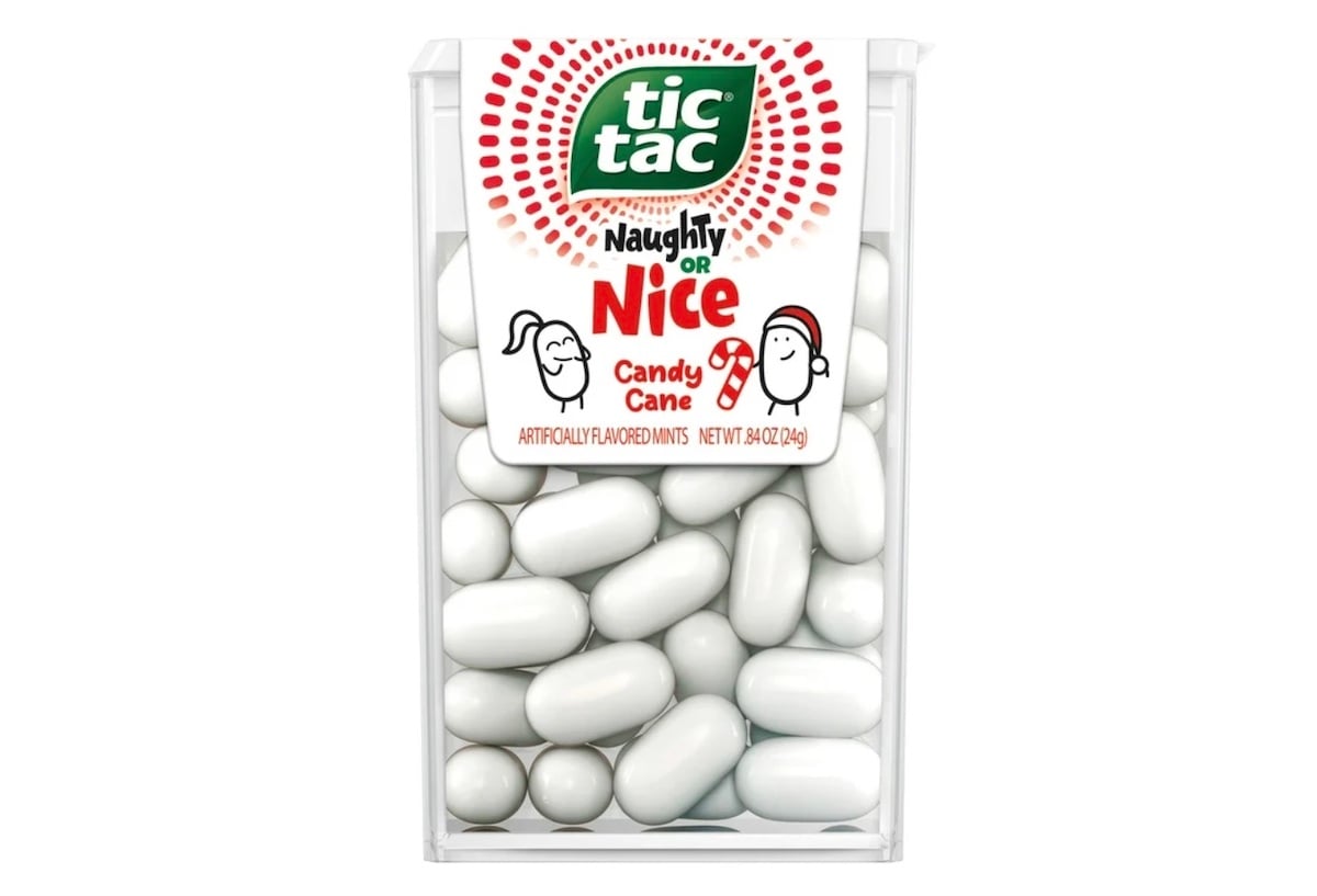 A clear plastic container of Tic Tac mints labeled "Naughty or Nice Candy Cane," featuring holiday-themed graphics and drawings of playful faces, with white mints visible inside.