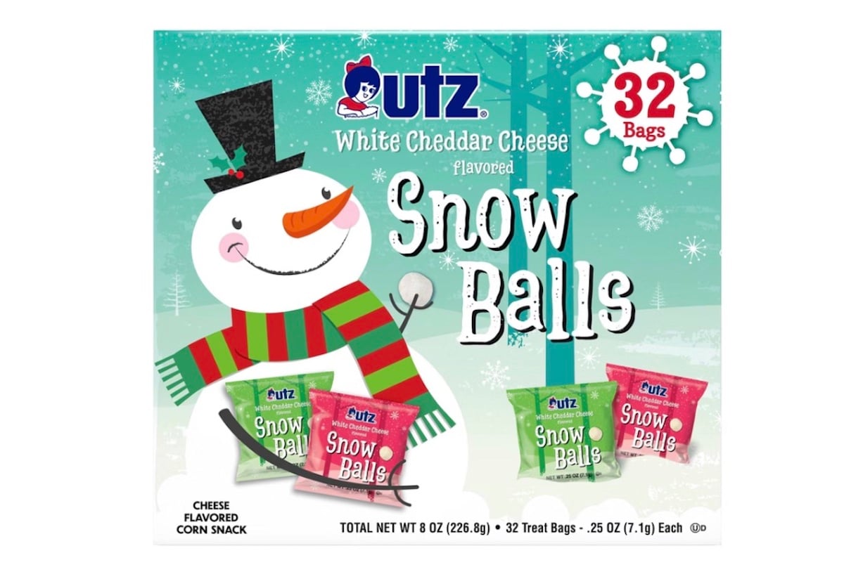 A festive Utz snack box features a smiling snowman in a scarf and top hat, advertising 32 bags of white cheddar cheese flavored "Snow Balls" corn snacks, with images of the individual snack bags at the bottom.
