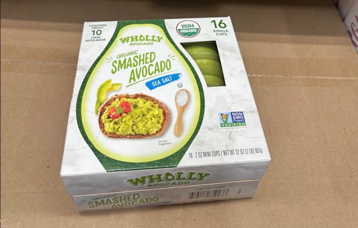 A box of Wholly Avocado Organic Smashed Avocado with sea salt, featuring a picture of avocado spread on toast. The package contains 16 single cups and is labeled USDA Organic and Non-GMO.