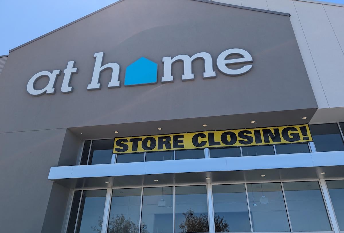 The storefront of an At Home store with a large yellow and black banner that reads "STORE CLOSING!" hanging above the entrance.