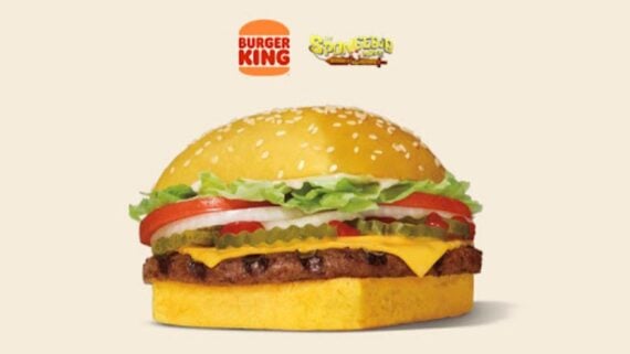 A Burger King cheeseburger with a square yellow bun, cheese, pickles, onions, tomato, and lettuce. Above the burger are the Burger King and SpongeBob SquarePants logos on a light background.