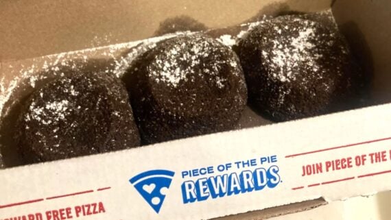 Three chocolate lava cake desserts topped with powdered sugar are arranged in a row inside a cardboard box labeled "Piece of the Pie Rewards.