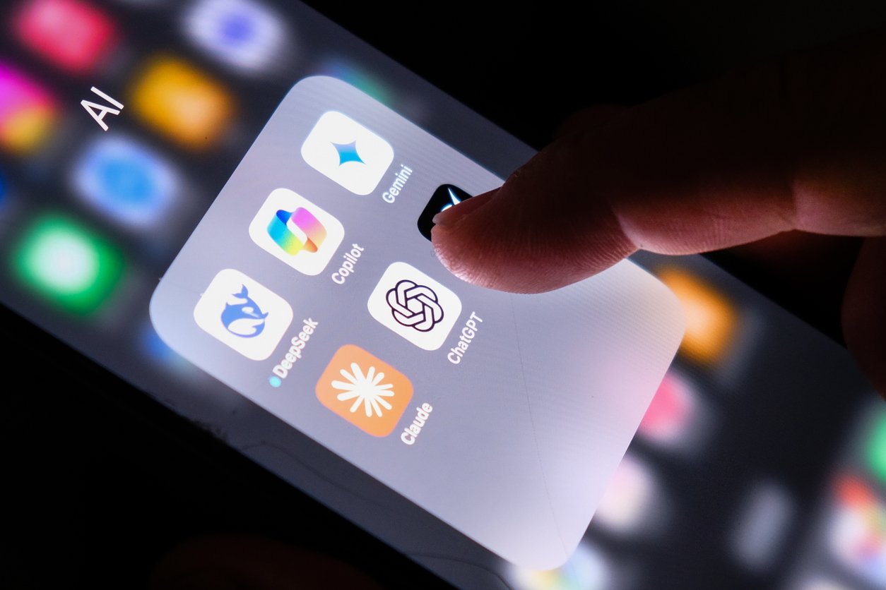 A finger is about to tap the ChatGPT app icon on a smartphone screen. Other visible AI-related app icons include Copilot, Gemini, DeepSeek, and Claude, all grouped in a folder labeled "AI.