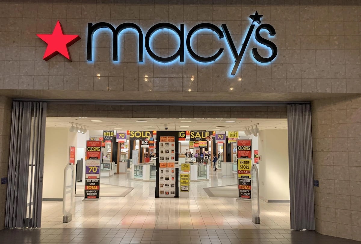 The entrance of a Macy's store with bright signage displays multiple "Store Closing," "Sale," and "70% Off" signs, indicating a going-out-of-business sale inside the shopping mall.