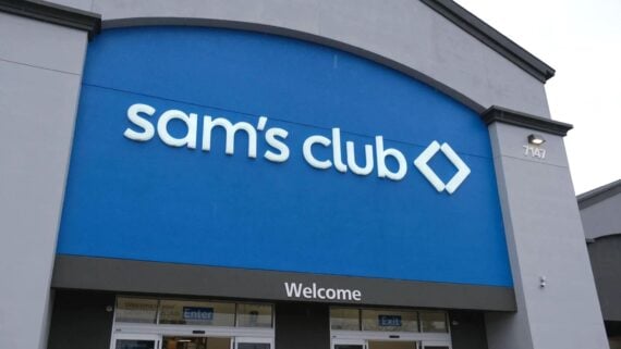 The front entrance of a Sam's Club store, featuring a large blue sign with the Sam's Club logo above the doors and the word "Welcome" visible below.