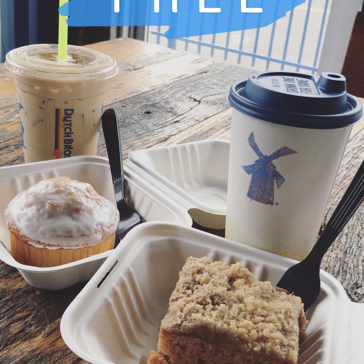 Iced coffee, a hot drink in a to-go cup, a muffin, and a piece of crumb cake sit in takeout containers on a wooden table. Both drinks and containers feature the Dutch Bros logo. The word "FREE" is partially visible above.