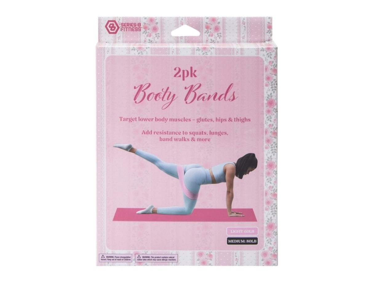 A pink and white box labeled "2pk Booty Bands" features a woman in workout attire on a yoga mat, demonstrating a leg lift exercise. The packaging highlights benefits for glutes, hips, and thighs.