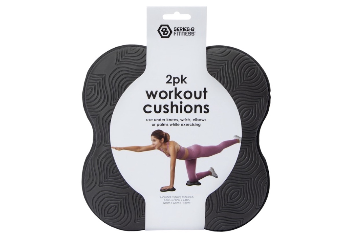 Two black, textured workout cushions in a pack. Packaging label shows a woman exercising on one cushion and reads: "2pk workout cushions—use under knees, wrists, elbows or palms while exercising.