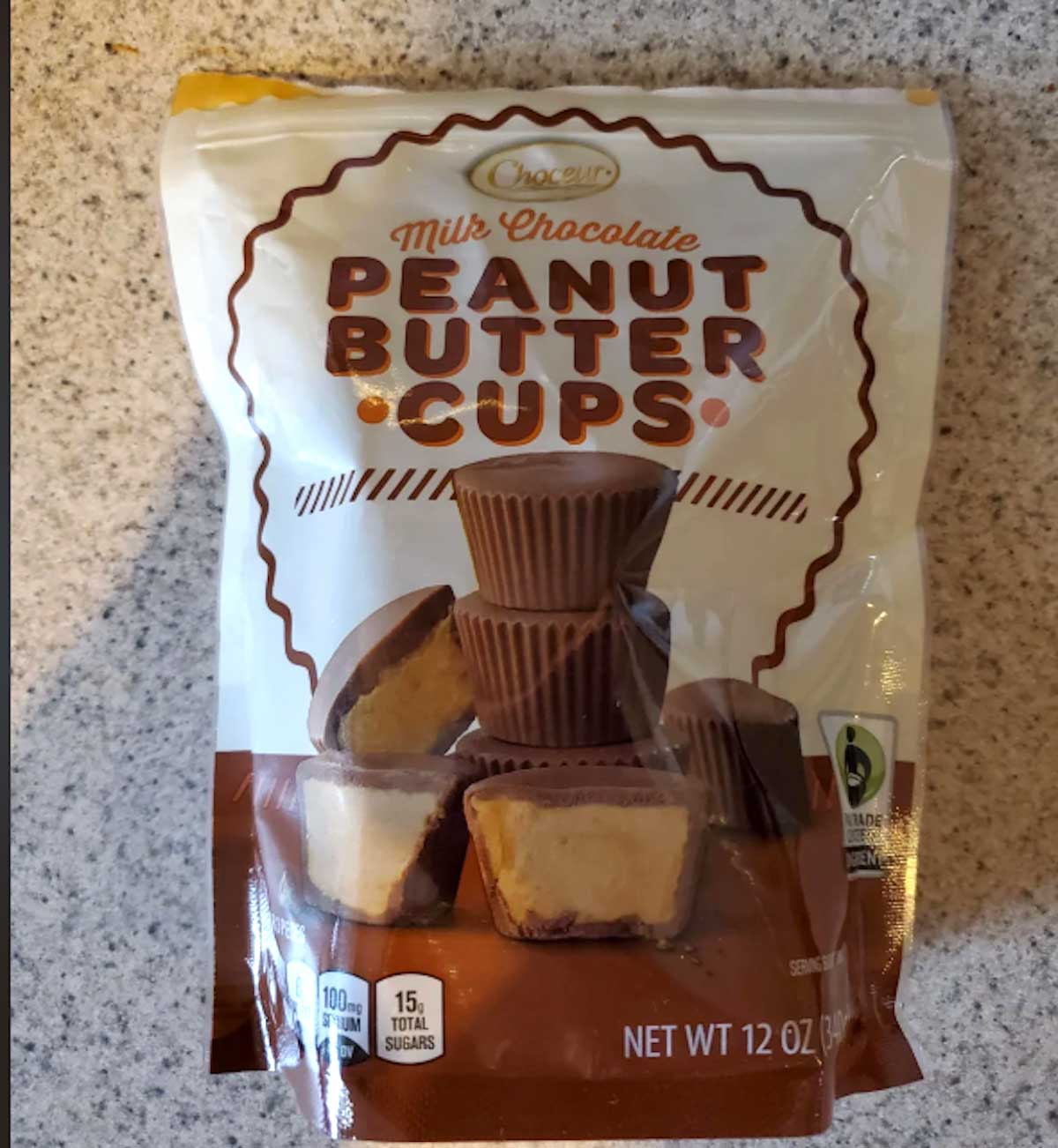 A bag of Choceur Milk Chocolate Peanut Butter Cups, one of the Aldi fan favorites, sits on a speckled countertop. The 12 oz package displays stacked peanut butter cups and tempting chocolate goodness.