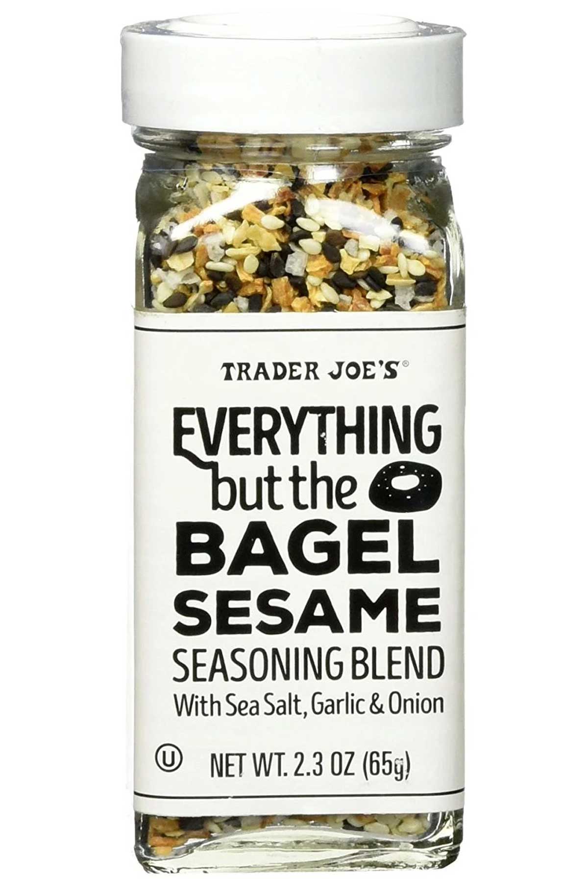 A clear glass jar of Trader Joe’s Everything but the Bagel Sesame Seasoning Blend with sea salt, garlic, and onion, featuring a white label and black text. Some say this mix of sesame seeds and spices is a bit overrated Trader Joe's product.