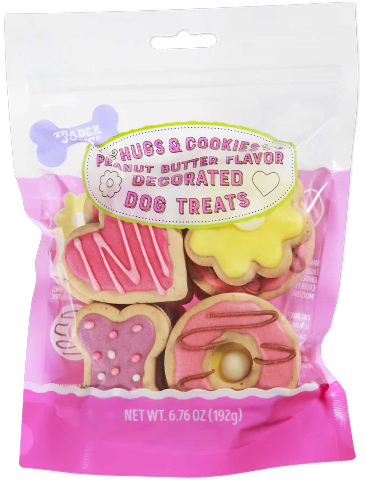 A clear and pink bag of Hugs & Cookies peanut butter flavor decorated dog treats, featuring assorted brightly frosted dog biscuits shaped like hearts and doughnuts. The bag contains 6.76 oz (192g) of treats.