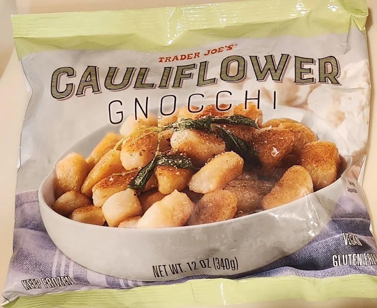 A bag of Trader Joe’s Cauliflower Gnocchi, featuring a bowl of browned gnocchi garnished with herbs on the packaging. The bag is labeled as vegan, gluten-free, and net weight 12 oz (340g).