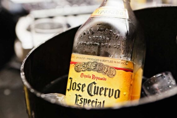 A close-up of a Jose Cuervo Especial tequila bottle chilled in a black container with ice cubes. The label and condensation on the bottle are clearly visible, often cited among the worst tequilas to buy by some enthusiasts.