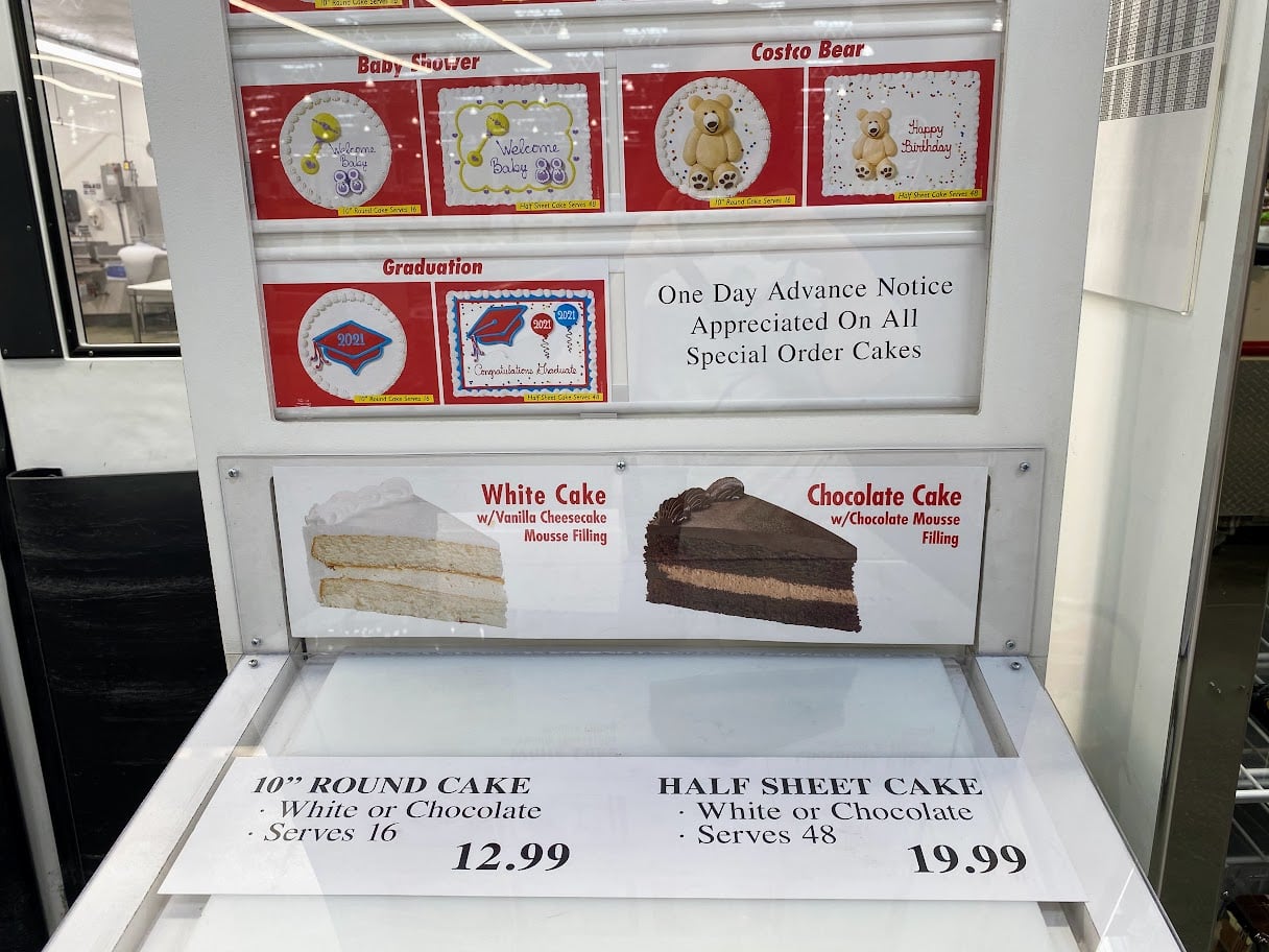A bakery display shows cake options and prices. There are designs for baby showers, graduations, and bears. White and chocolate mousse cakes are offered: 10" round cake for $12.99 (serves 16) and half sheet cake for $24.99 (serves 48).