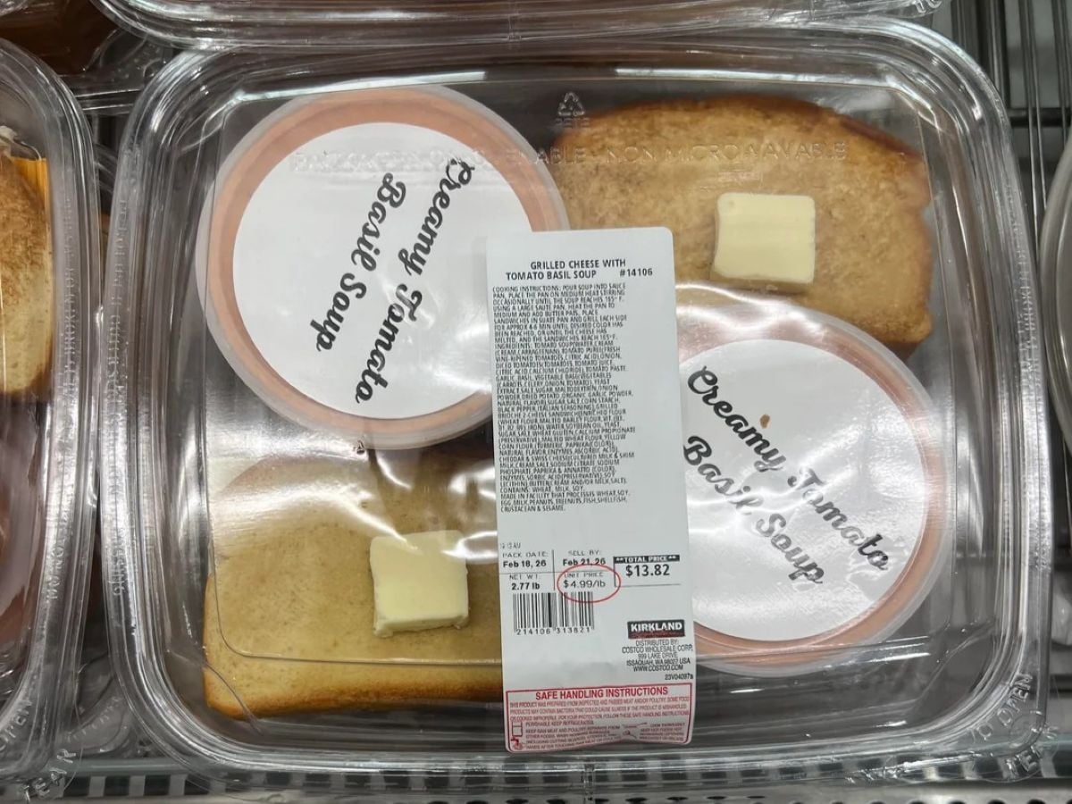 Plastic container with two slices of bread, two pats of butter, and two cups labeled “Creamy Tomato Basil Soup.” The container has a white price label and is displayed in a refrigerated section.
