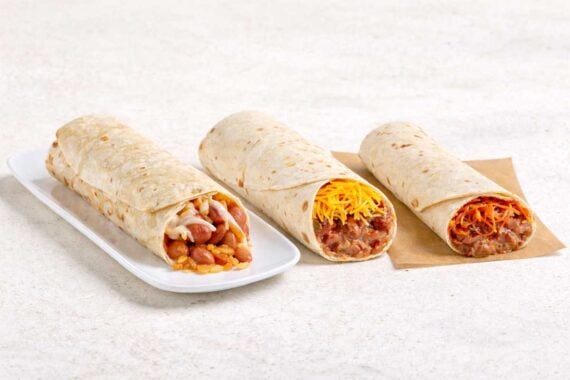 Three of the best bean and cheese burritos rest on a light surface; two are wrapped in tortillas, while one is cut open on a white plate, revealing hearty beans and melted cheese inside.