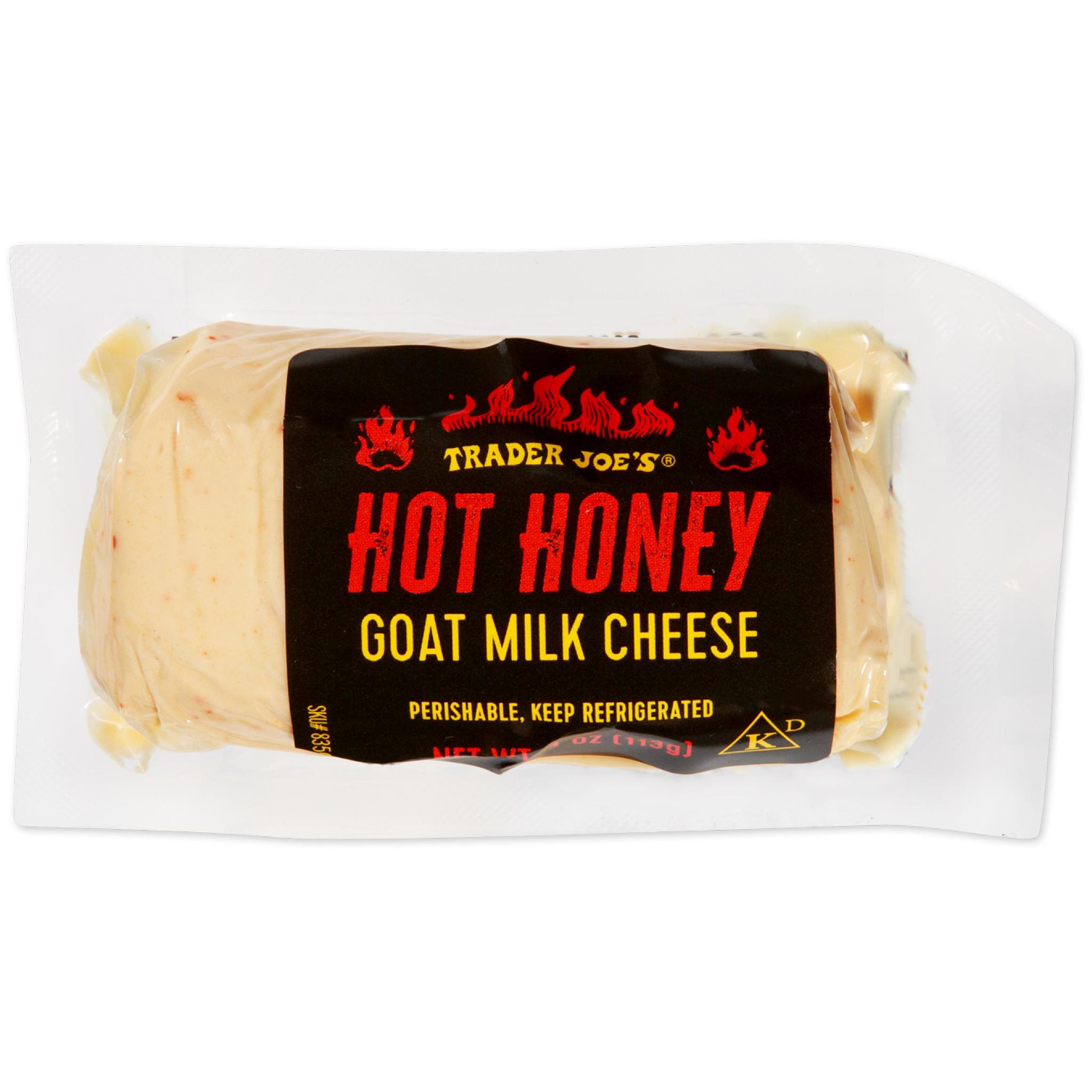 A packaged block of Trader Joe’s Hot Honey Goat Milk Cheese, wrapped in clear plastic with a black label featuring red and yellow text and flame graphics, indicating it is perishable and should be kept refrigerated.