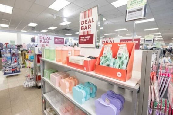 A store display labeled &ldquo;Deal Bar&rdquo; features pastel-colored containers and accessories organized on white shelves, with price tags and signs indicating deals and discounts in a brightly lit retail environment.
