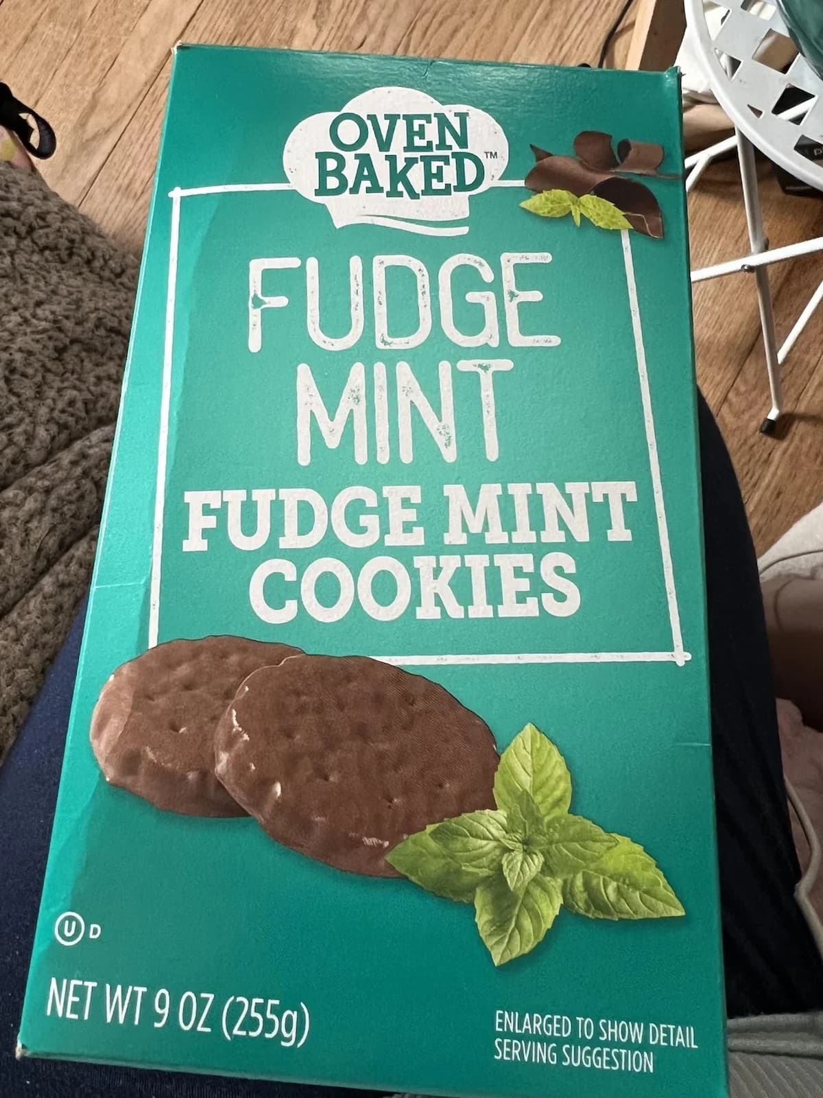 A box of Oven Baked Fudge Mint Cookies. The packaging is teal with images of two chocolate-covered mint cookies and mint leaves. The net weight is 9 oz (255g).