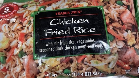 A package of Trader Joe's chicken fried rice, featuring stir fried rice with vegetables, seasoned dark chicken meat, and eggs. The packaging notes it cooks in about 5 minutes and weighs 1 lb 4 oz (567g).