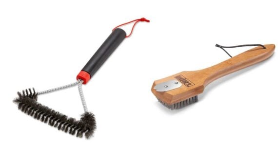 Two grill cleaning brushes: one with a black handle, twisted wire bristles, and a red hanging loop; the other with a wooden handle, metal scraper, wire bristles, and a black hanging loop&mdash;unaffected by any Weber grill brush recall.