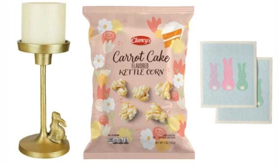 A gold candle holder with a rabbit figurine, a bag of Clancy&rsquo;s carrot cake flavored kettle corn from new Aldi products, and two napkins with pastel bunny designs on a white background.