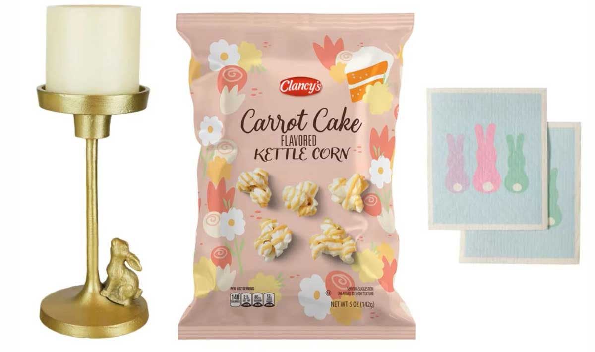 A gold candle holder with a rabbit figurine, a bag of Clancy’s carrot cake flavored kettle corn from new Aldi products, and two napkins with pastel bunny designs on a white background.