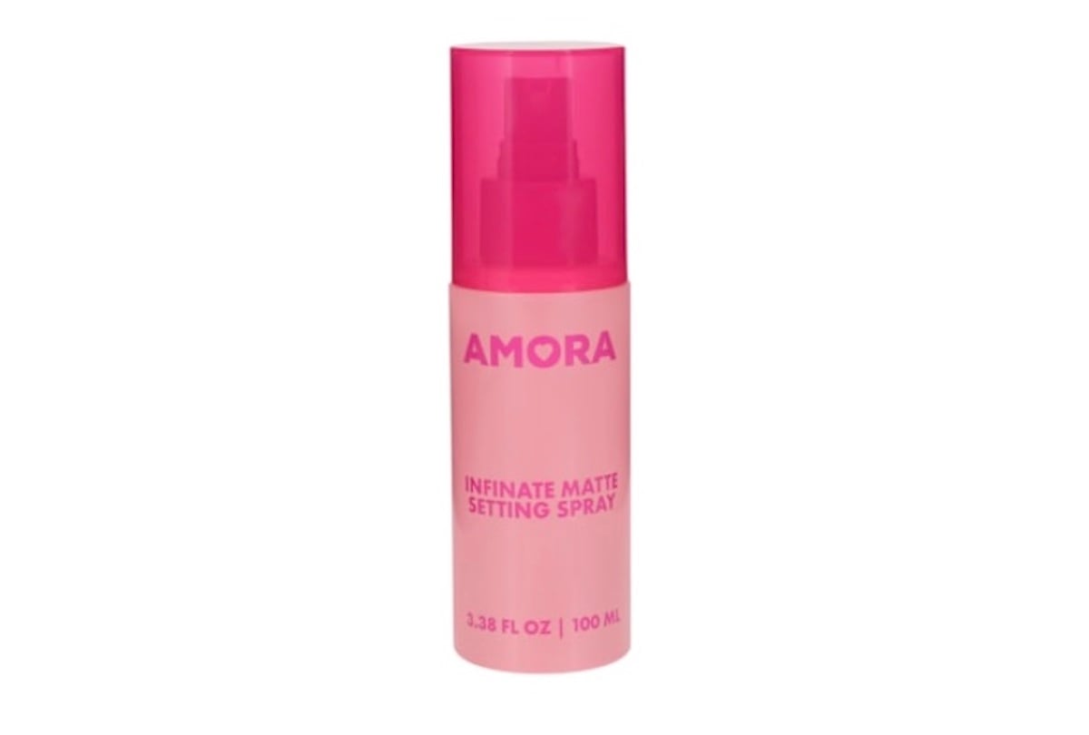 A pink bottle of AMORA Infinate Matte Setting Spray with a matching pink cap, labeled as 3.38 FL OZ (100 mL)—a must-have among beauty products for a flawless, lasting finish.