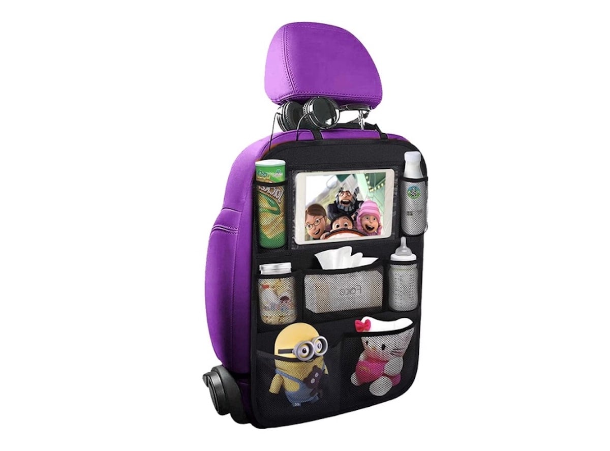 A purple car seat with a black backseat organizer holding drinks, toys, a tissue box, a water bottle, a can, snacks, and a tablet displaying an animated show—perfect for spring break road trips.