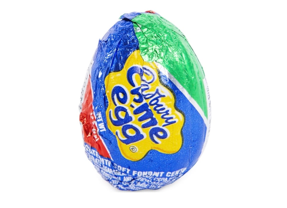 A Cadbury Creme Egg wrapped in colorful blue, red, green, and yellow foil with the Cadbury logo visible, set against a white background.