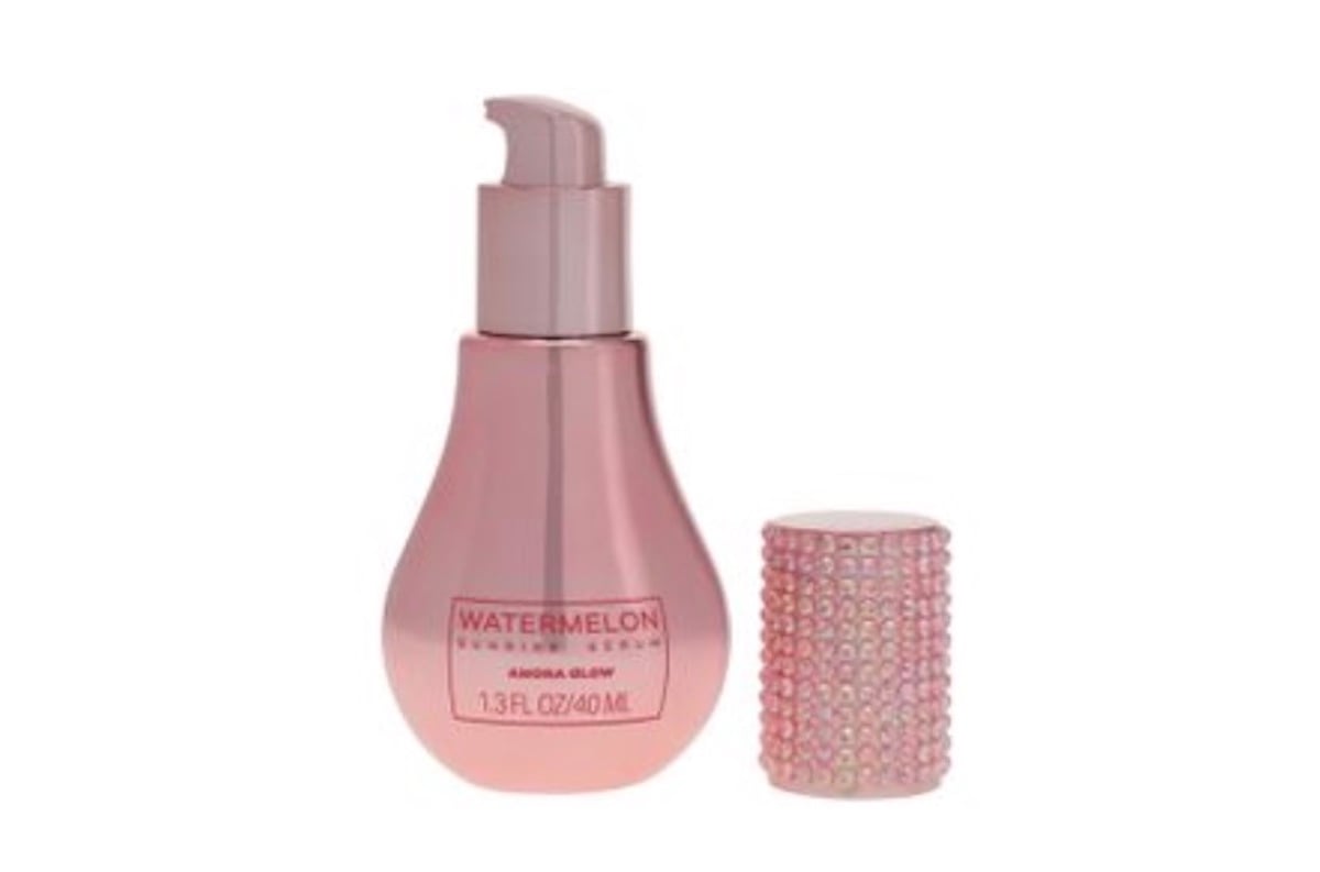 A pink pump bottle labeled "Watermelon Evening Serum, Aqua Glow, 1.3 fl oz/40 mL" is shown with its jeweled pink cap placed beside it, standing out among beauty products for its radiant design.