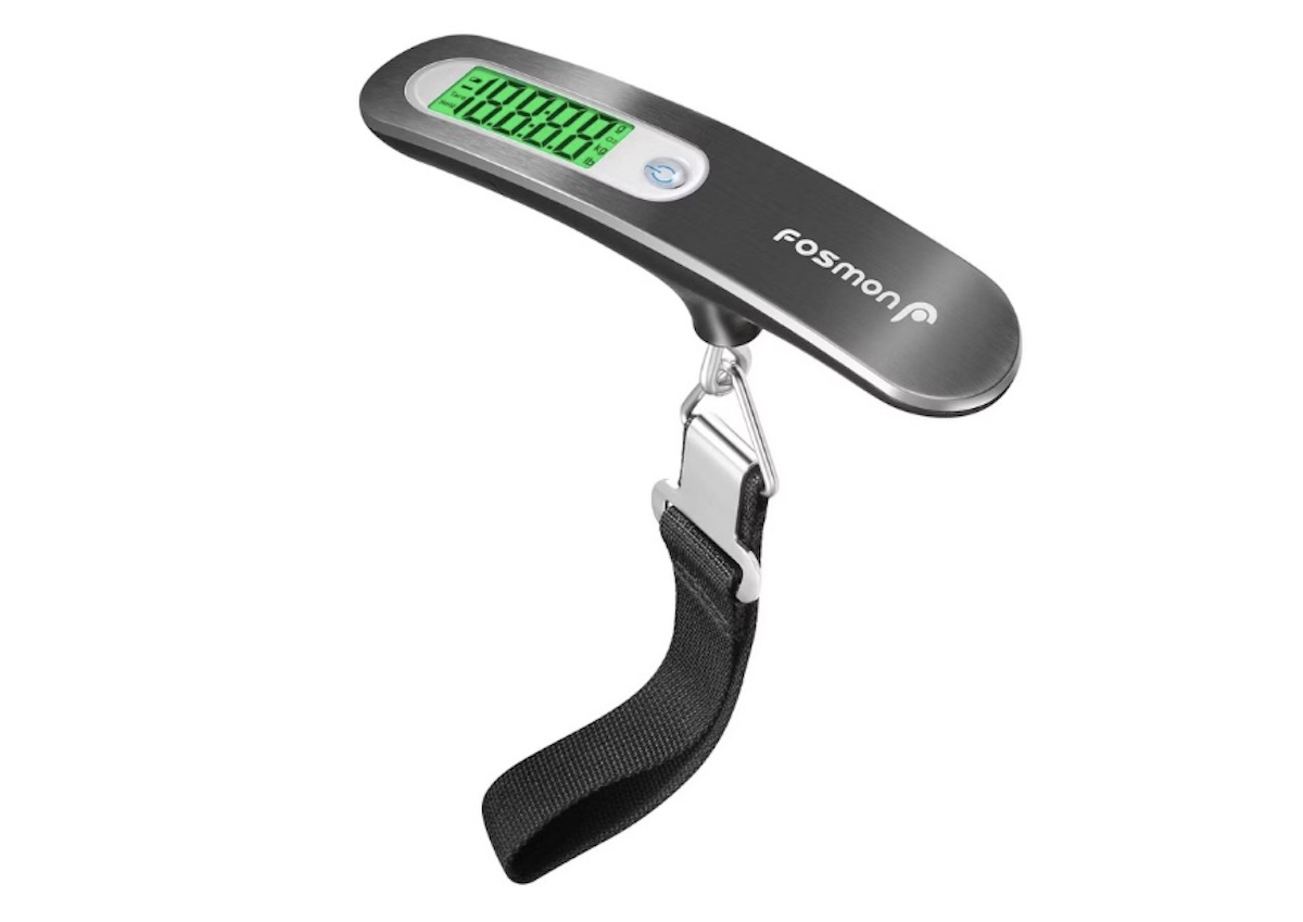 A digital luggage scale with a green backlit display, perfect for spring break trips. It features a metal top labeled "Fosmon" and a black strap with a metal clip for attaching to your luggage.