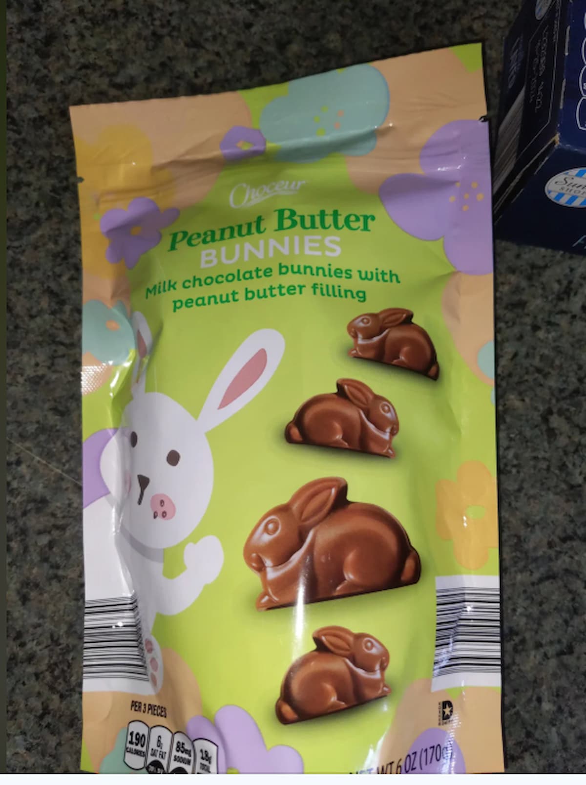 A bag of Choceur Peanut Butter Bunnies featuring illustrations of chocolate bunny candies and a cartoon bunny, labeled "Milk chocolate bunnies with peanut butter filling," on a green and yellow background with flowers.