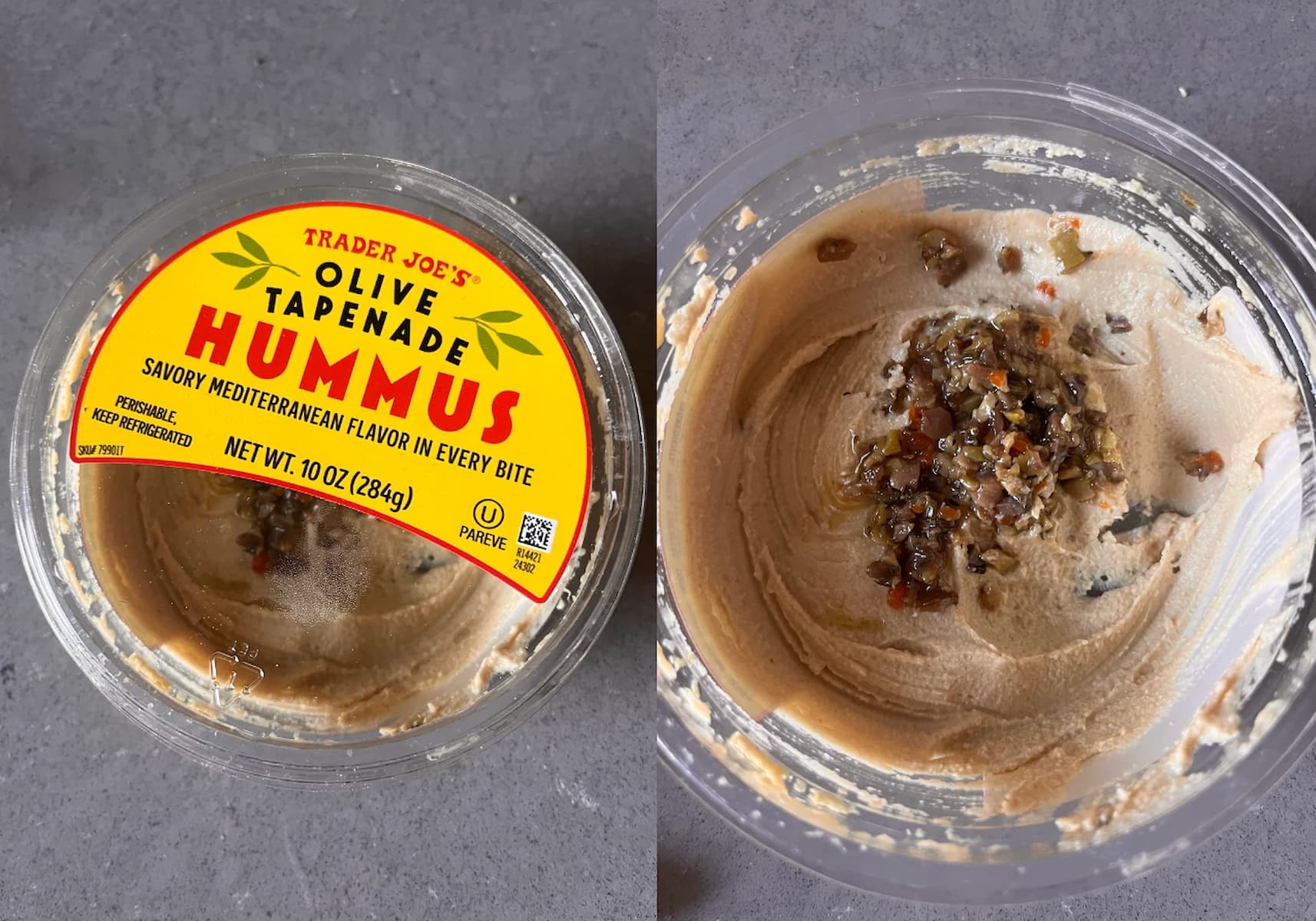 A plastic container of Trader Joe’s Olive Tapenade Hummus sits open on a gray surface, showing creamy hummus with a topping of chopped olive tapenade in the center.