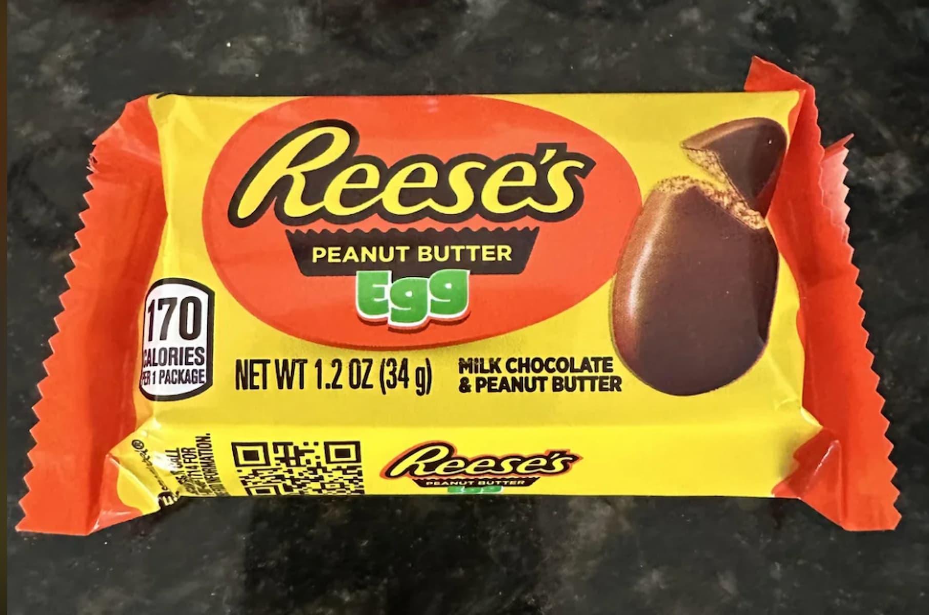 A Reese's Peanut Butter Egg candy in yellow and orange packaging, featuring a photo of the chocolate egg and text indicating it has milk chocolate and peanut butter and contains 170 calories per package.