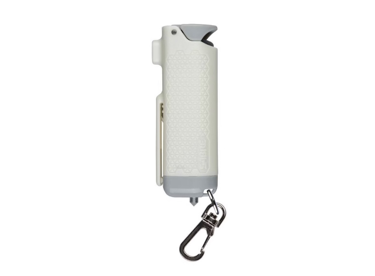 A white pepper spray canister with a textured grip, gray safety cap, metal clip on the side, and a keychain attachment—perfect for added safety during spring break adventures.