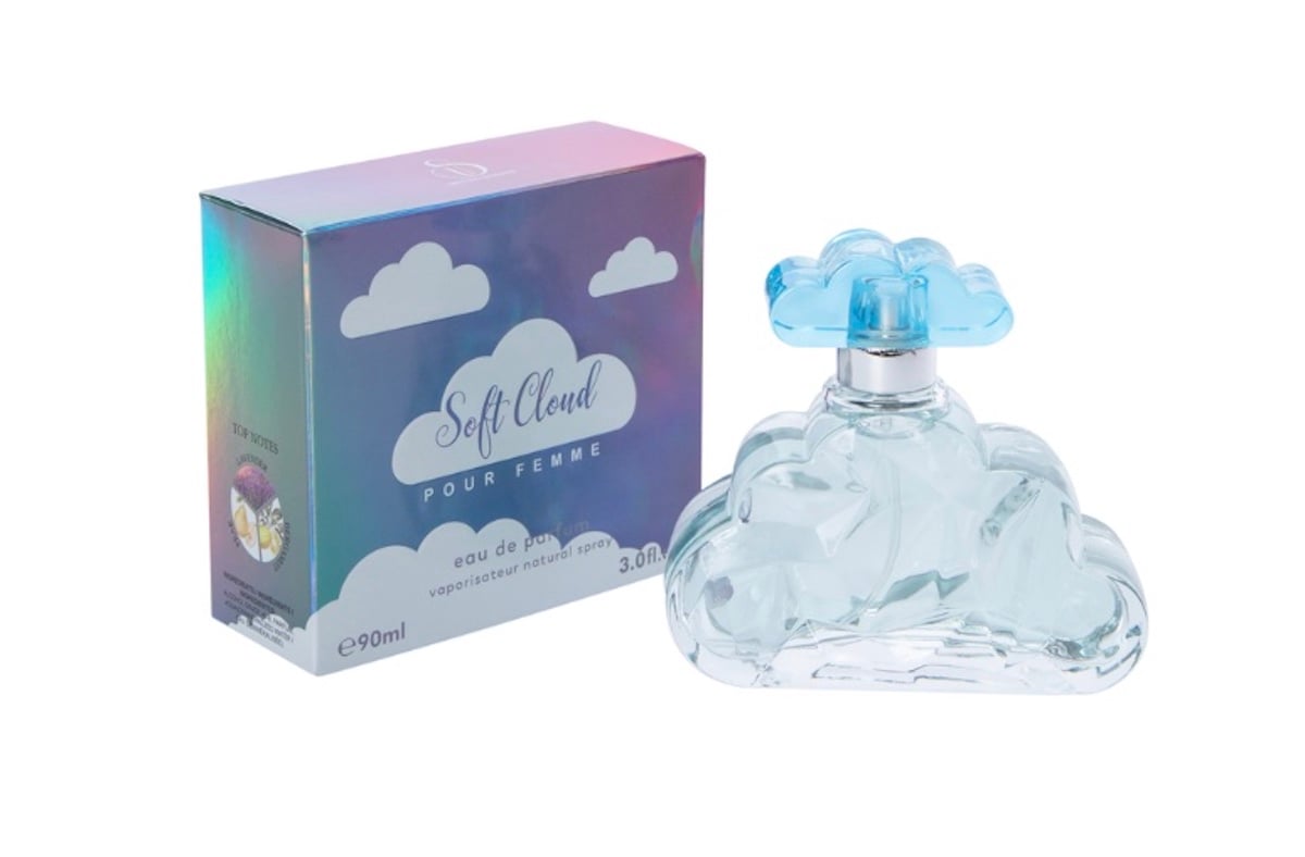 A perfume called "Soft Cloud Pour Femme"—a stunning addition to your beauty products—comes in a box with white clouds and iridescent colors, beside a cloud-shaped glass bottle with a blue cap, holding 90ml of fragrance.