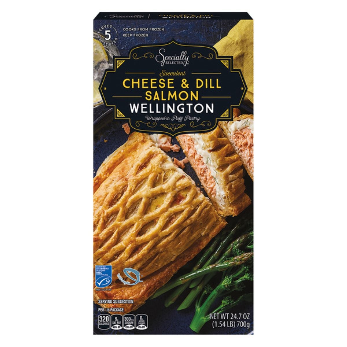 A box of Specialty Selected Cheese & Dill Salmon Wellington is shown, featuring an image of the pastry with salmon filling, cut into pieces, and served with asparagus on the front of the package. Net weight is 24.7 oz (700g).