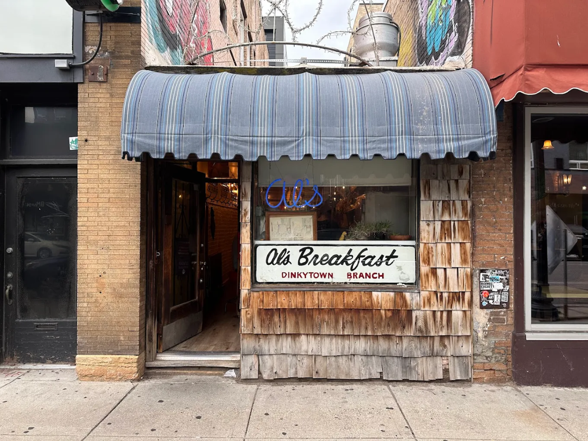 The exterior of Al's Breakfast diner features a blue-striped awning, neon sign, and a white sign reading "Al's Breakfast Dinkytown Branch" on weathered wood siding. The entrance door is open on the left.