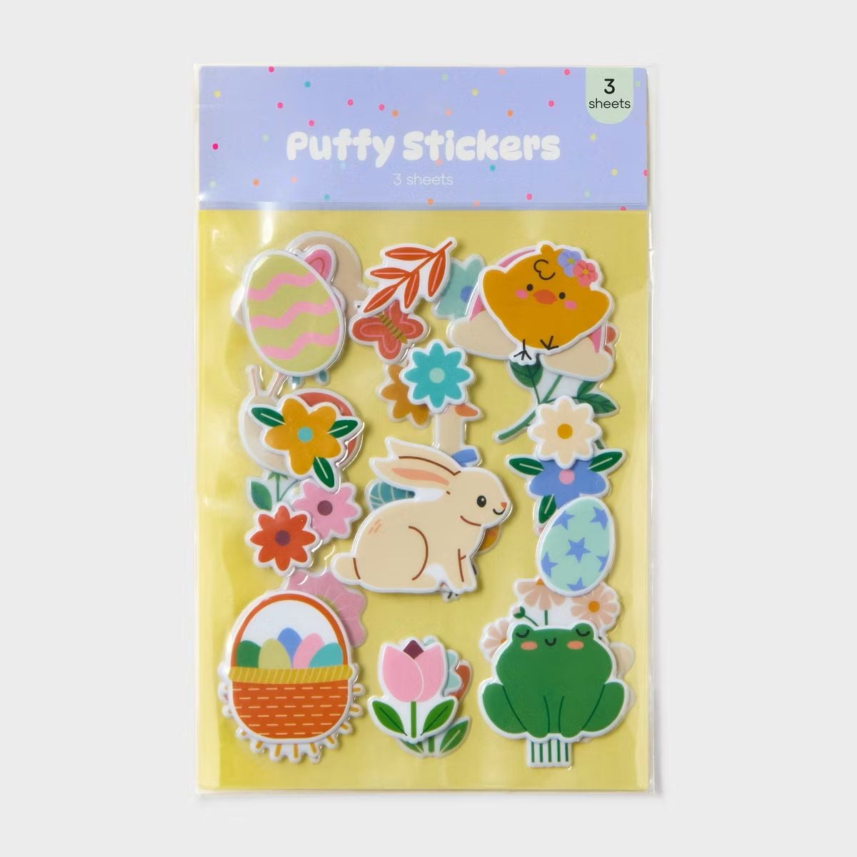 A package of Puffy Stickers featuring colorful designs, including a chick, a bunny, a frog, an Easter egg, a basket with eggs, tulips, and various flowers. The background is yellow and the package contains three sheets.