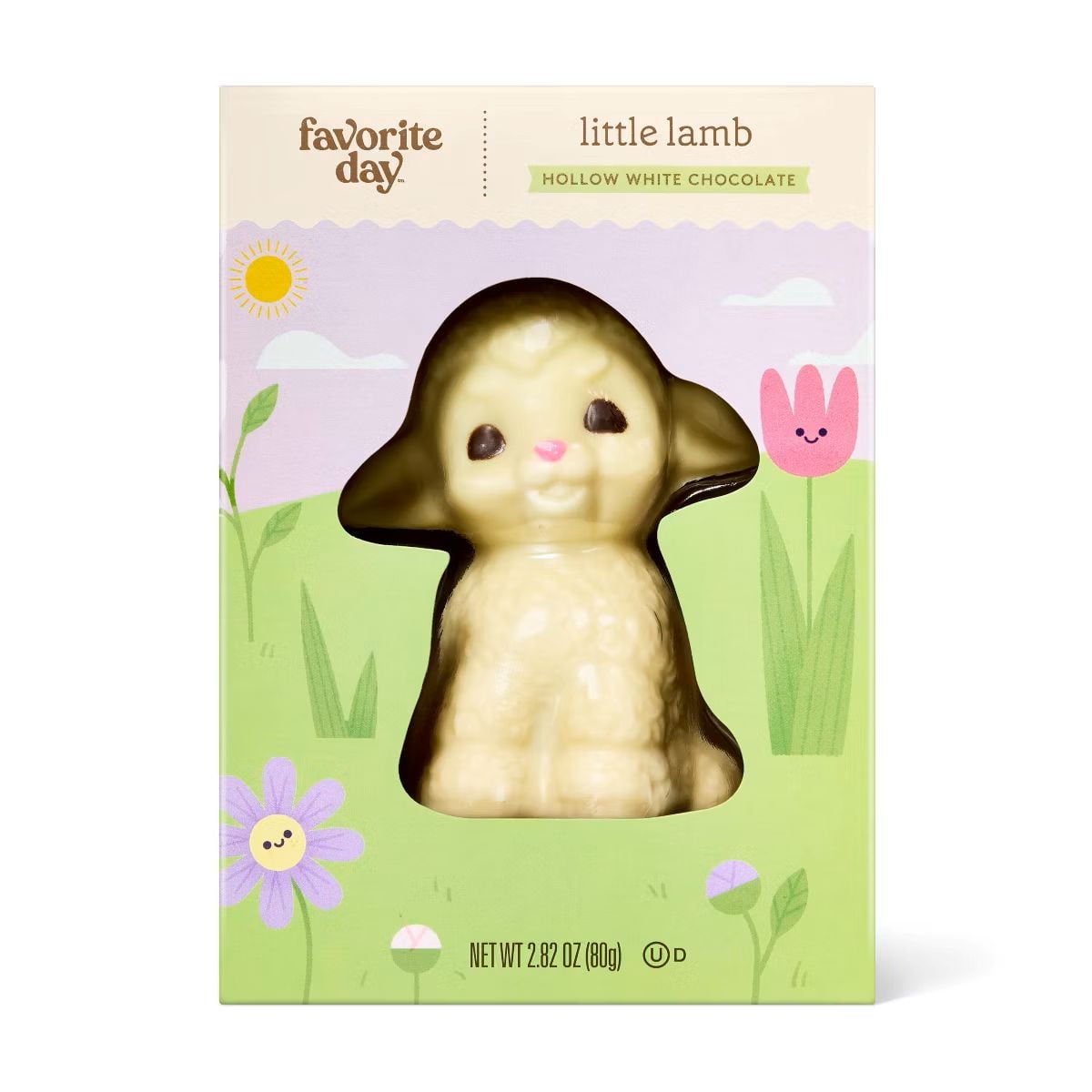 A boxed hollow white chocolate lamb by Favorite Day, displayed against pastel packaging with flowers, grass, a sun, and a pink bunny illustration. The lamb has dark ears and eyes, and a pink nose. Net weight: 2.82 oz.