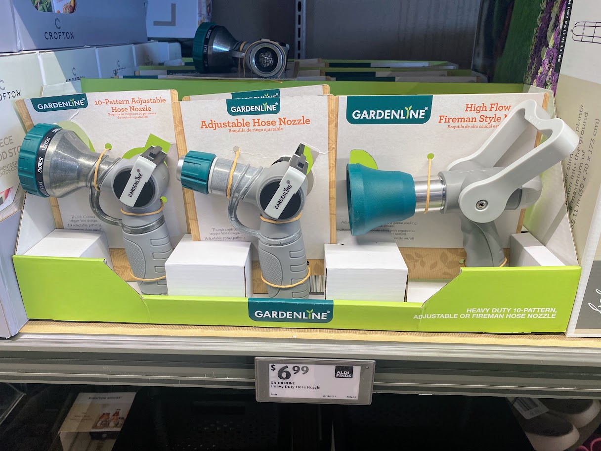 Three Gardenline hose nozzles on display in a store: two adjustable models on the left and one high-flow fireman style on the right. Price tag below shows $6.99 each.